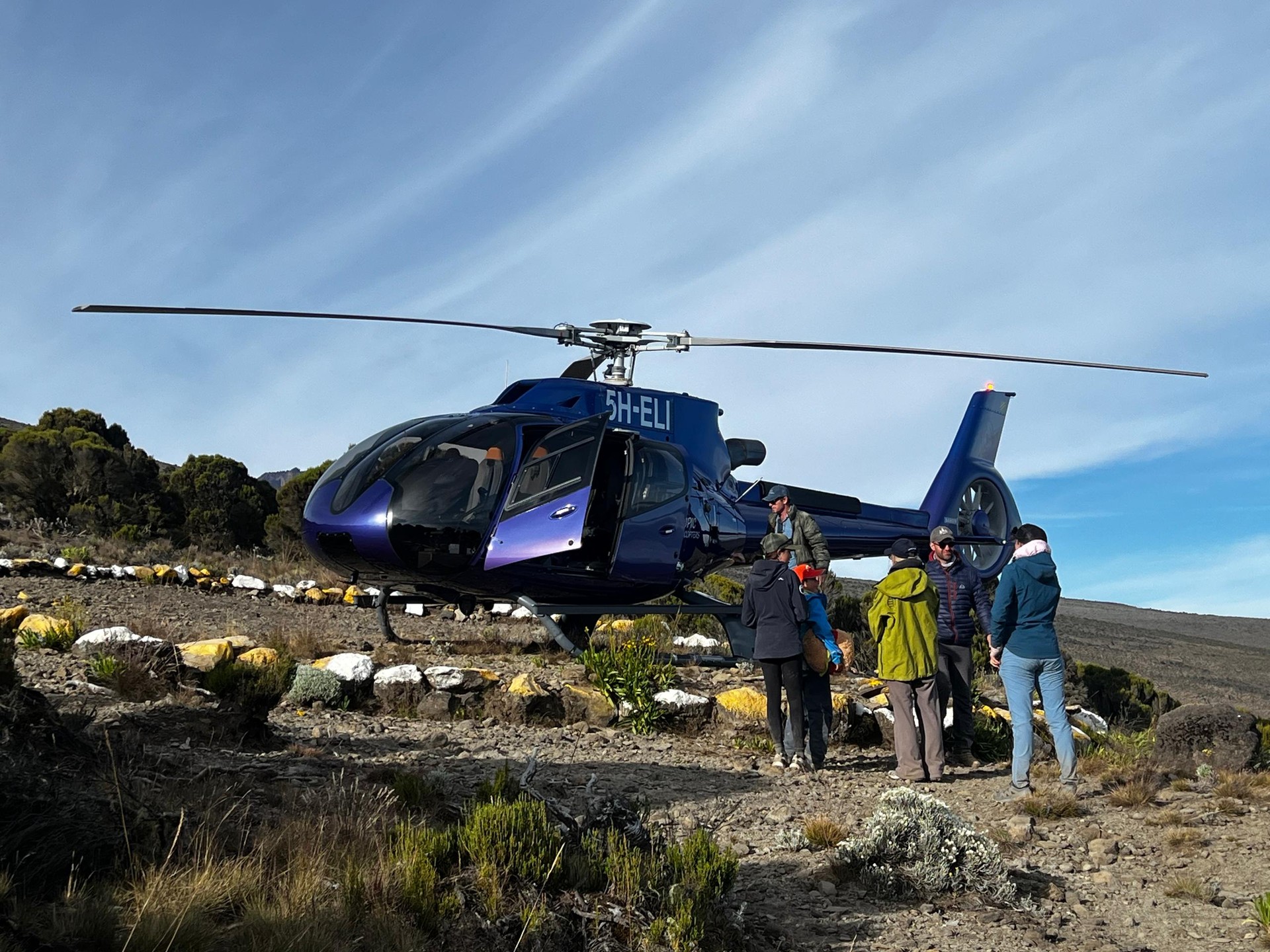 Helicopter and trekkers on Mount Kilimanjaro during a high-altitude mountain expedition