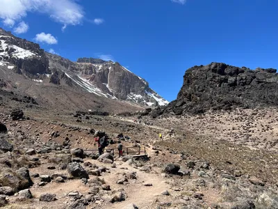 Hikers following a trail through the dramatic volcanic landscape of Mount Kilimanjaro